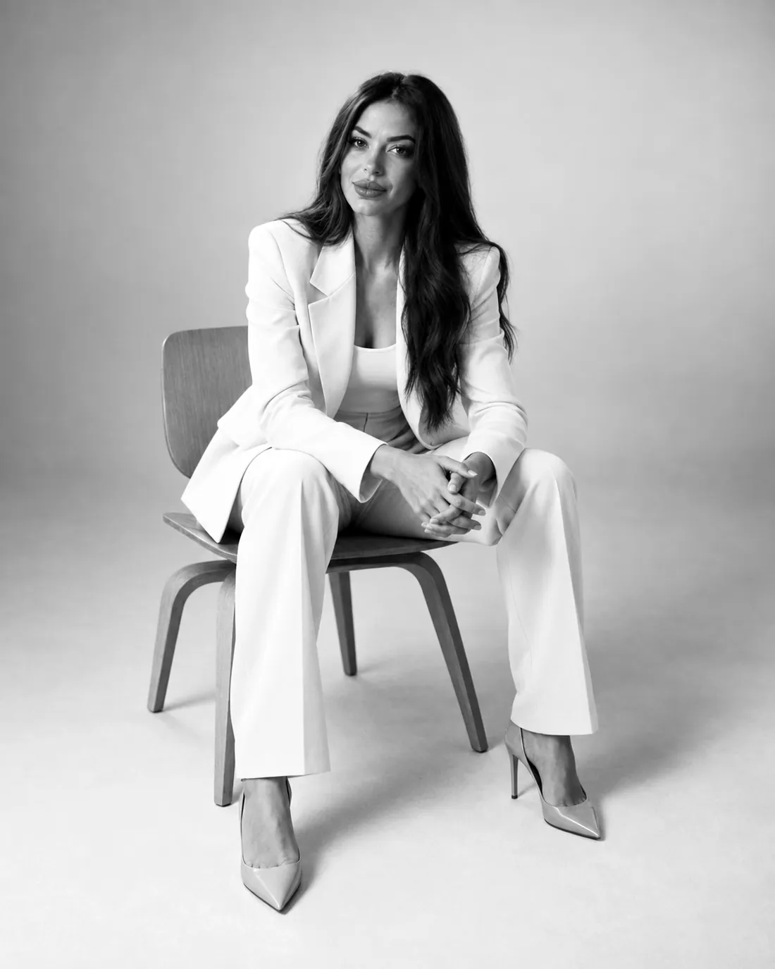 Samantha del Castillo con traje blanco, sentada
